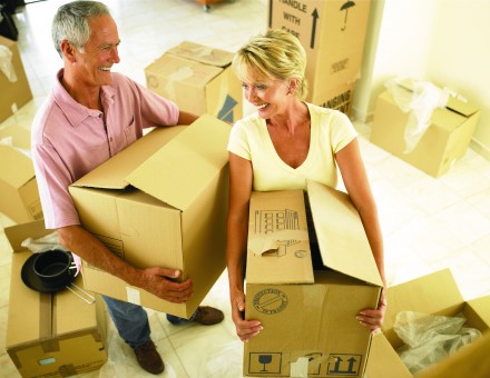 couple holding moving boxes and smiling