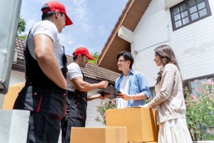 A young couple signs a clipboard from a moving company.
