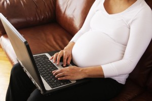 pregnant woman typing on a laptop