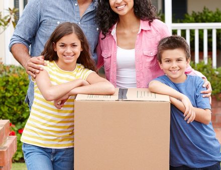 family posing in front of moving boxes