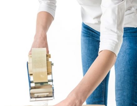 woman sealing moving box with tape