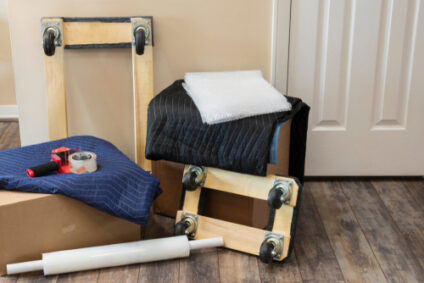 A pile of moving supplies, including wheeled carts, is on the floor.