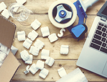 Packing materials all laid out on a table next to glass and a laptop. What Do I Need to Pack Everything I Have?
