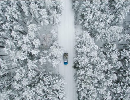 Car driving on a snowy single-lane road in the woods
