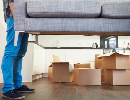 Person lifting couch with moving boxes in background