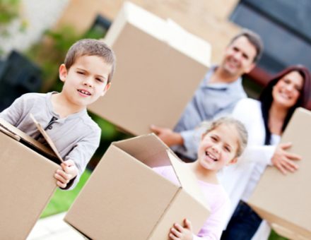 family moving holding cardboard boxes