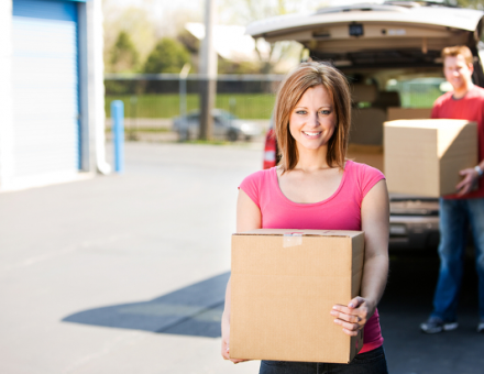 Couple unloading cardboard boxes from truck to put into storage