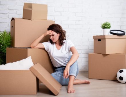 Stressed woman sitting with cardboard boxes on moving day