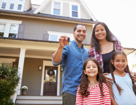 Family Holding Keys To New Home On Moving In Day