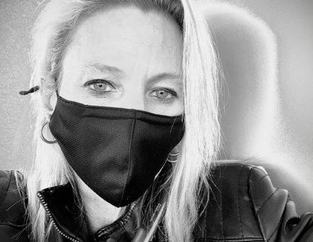 Black and white selfie of a woman in a black face mask