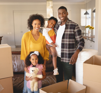 family smiling at the camera with empty moving boxes around them