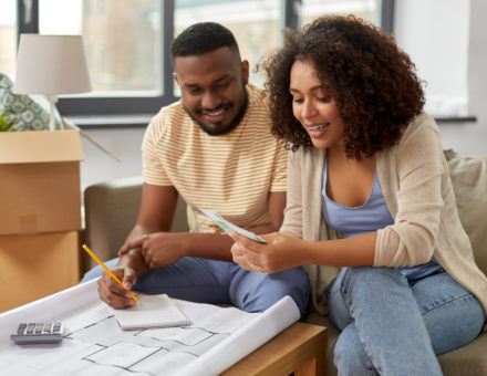 couple with blueprint and calculator counting money to create a moving budget