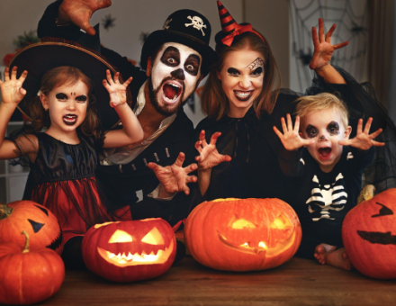 Family celebrating Halloween with costumes and pumpkins