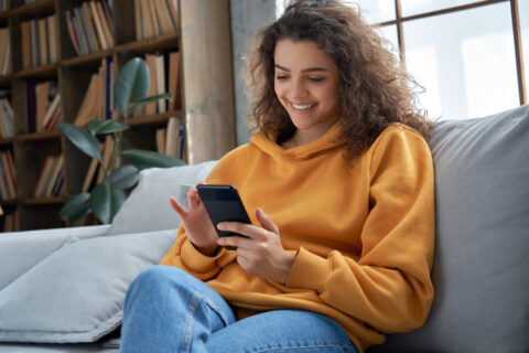 Woman sitting on the couch on a phone.