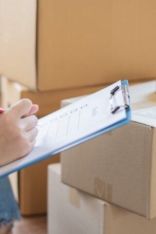 Woman next to boxes with a checklist.