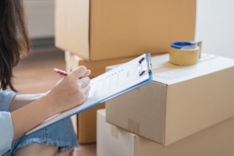 Woman next to boxes with a checklist.