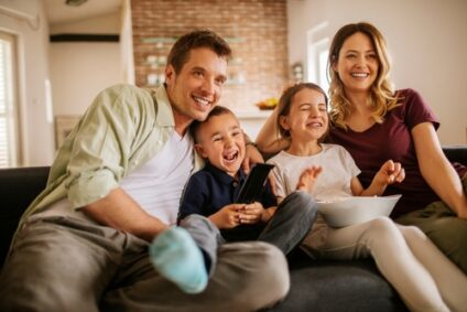 Two parents and two children laugh on the couch.