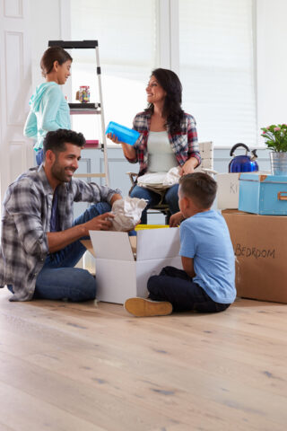 A family sitting together in their home with boxes behind them.