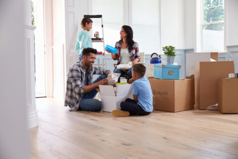 A family sitting together in their home with boxes behind them.