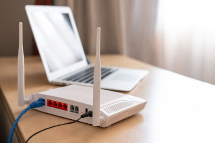 A laptop next to a router.