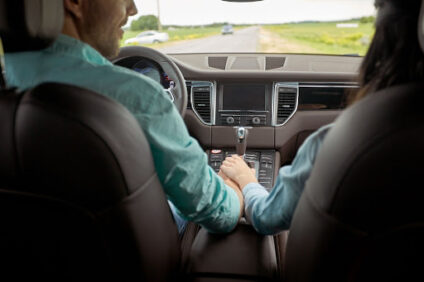 A couple holding hands in the front seats of their car.