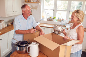 A middle-aged couple packing kitchen items into boxes.