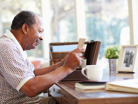A senior man reads an old letter taken from a wooden box.