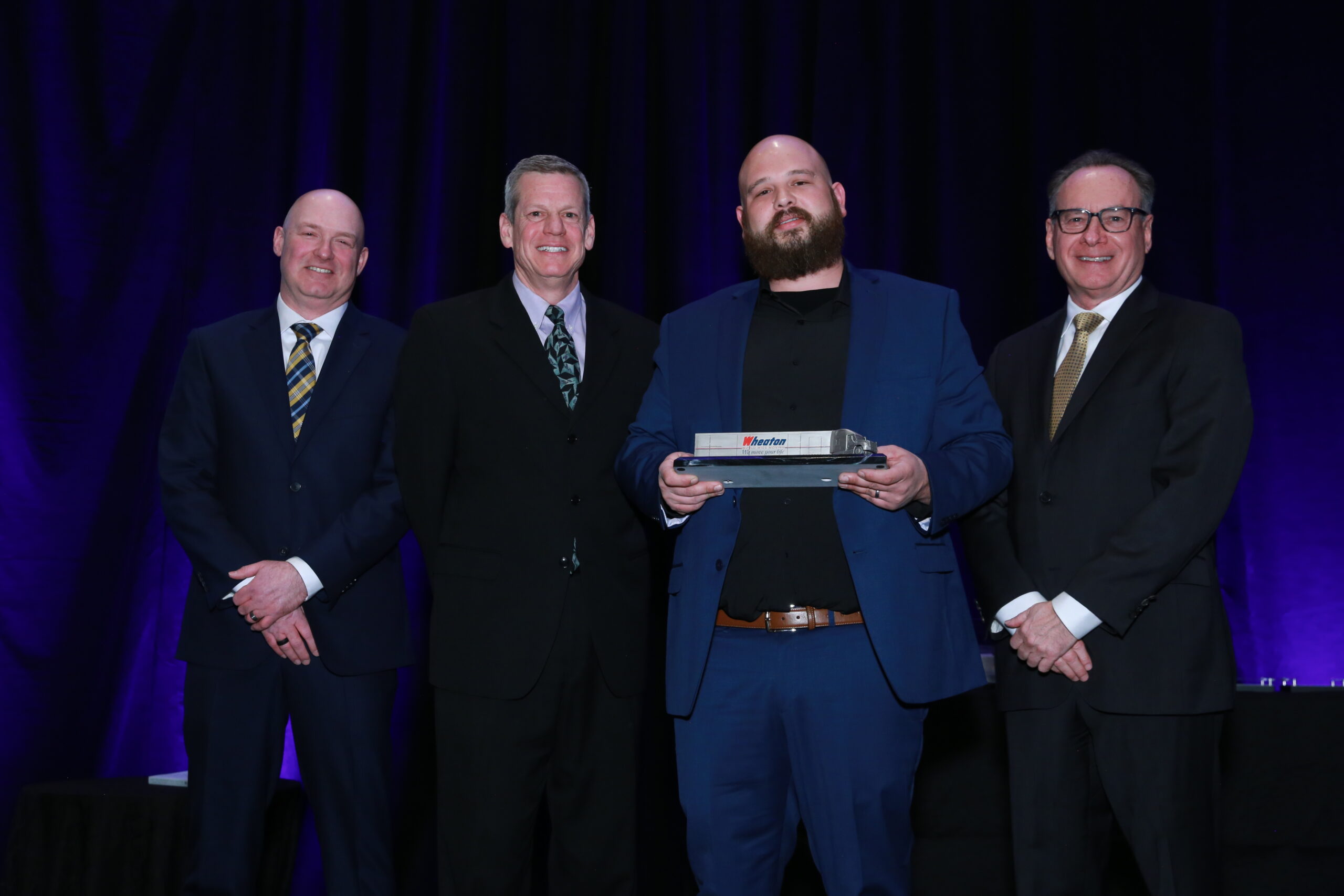 Wade Mark JR accepts award with group of people at Driver of the Year event. 