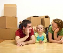 family smiling with moving boxes in the background