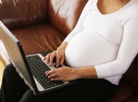 pregnant woman typing on a laptop
