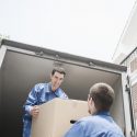 Two professional movers passing a box to each other.