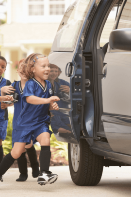 little kids in soccer jerseys running to get into van