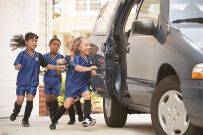 little kids in soccer jerseys running to get into van