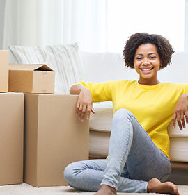 woman in yellow sweater sitting on the floor amidst moving boxes
