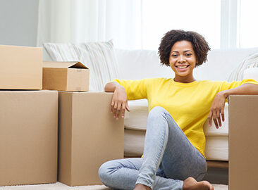 woman in yellow sweater sitting on the floor amidst moving boxes