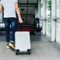 A closeup of a person rolling a suitcase.