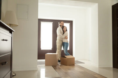 A couple holding each other and smiling in the entryway of their new home.