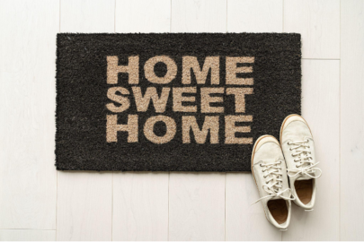 Door mat reading “home sweet home” with white tennis shoes in the corner