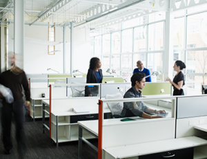 Employees moving and talking in bright office space.