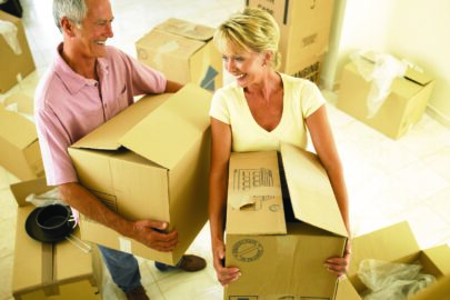 couple holding moving boxes and smiling