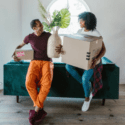 Two people sitting on a couch with boxes in their hands.
