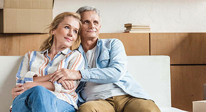 couple sitting and hugging with moving boxes behind them