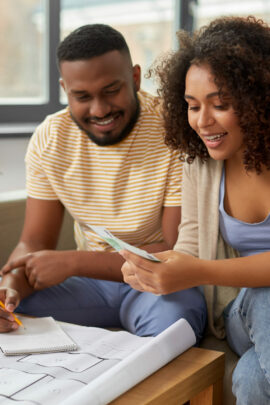 couple with blueprint and calculator counting money to create a moving budget