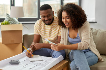 couple with blueprint and calculator counting money to create a moving budget
