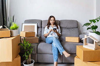 woman sitting on couch with moving boxes surrounding her