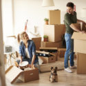 Two people unpacking boxes and smiling at each other.