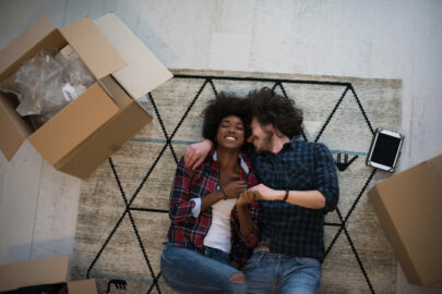 couple laying on rug in new home amidst moving boxes