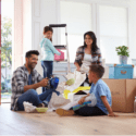 A family sitting together in their home with boxes behind them.