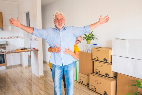 A couple posing in front of boxes and smiling.
