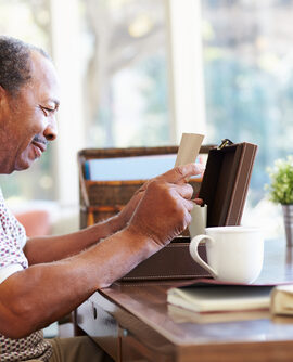 A senior man reads an old letter taken from a wooden box.